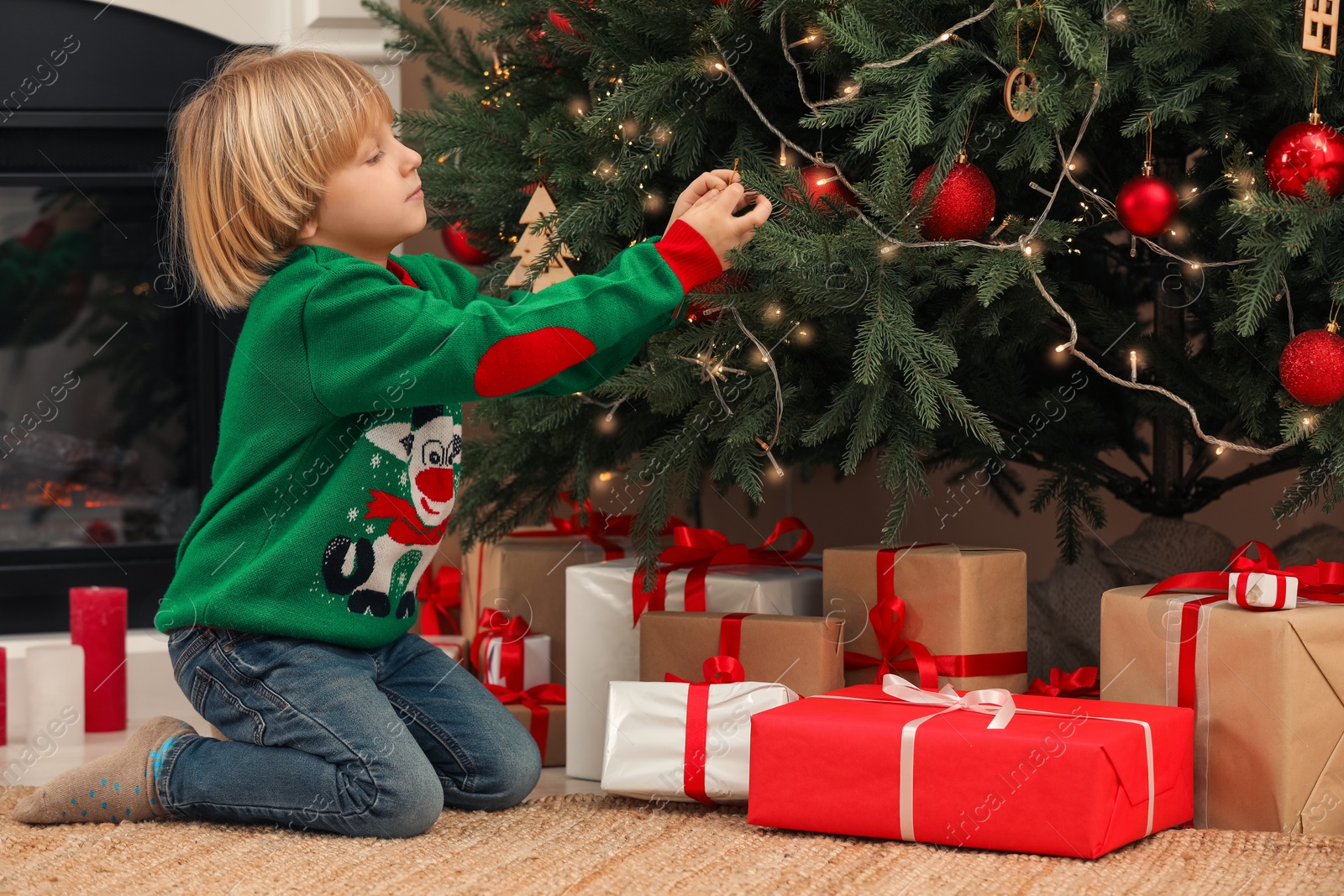 Photo of Little child decorating Christmas tree at home