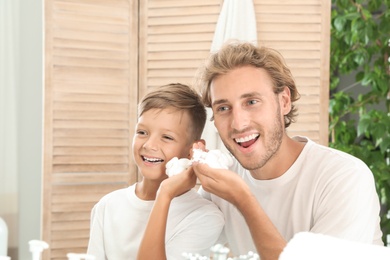 Photo of Father and son applying shaving foam in bathroom