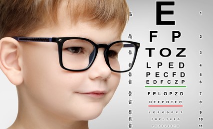 Image of Vision test. Cute little boy in glasses and eye chart on light grey background