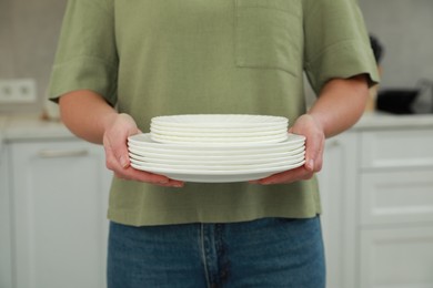 Photo of Woman holding plates in kitchen, closeup view