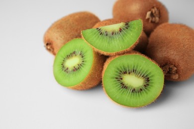 Heap of whole and cut fresh kiwis on white background, closeup. Space for text