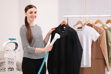 Photo of Woman steaming black shirt on hanger at home