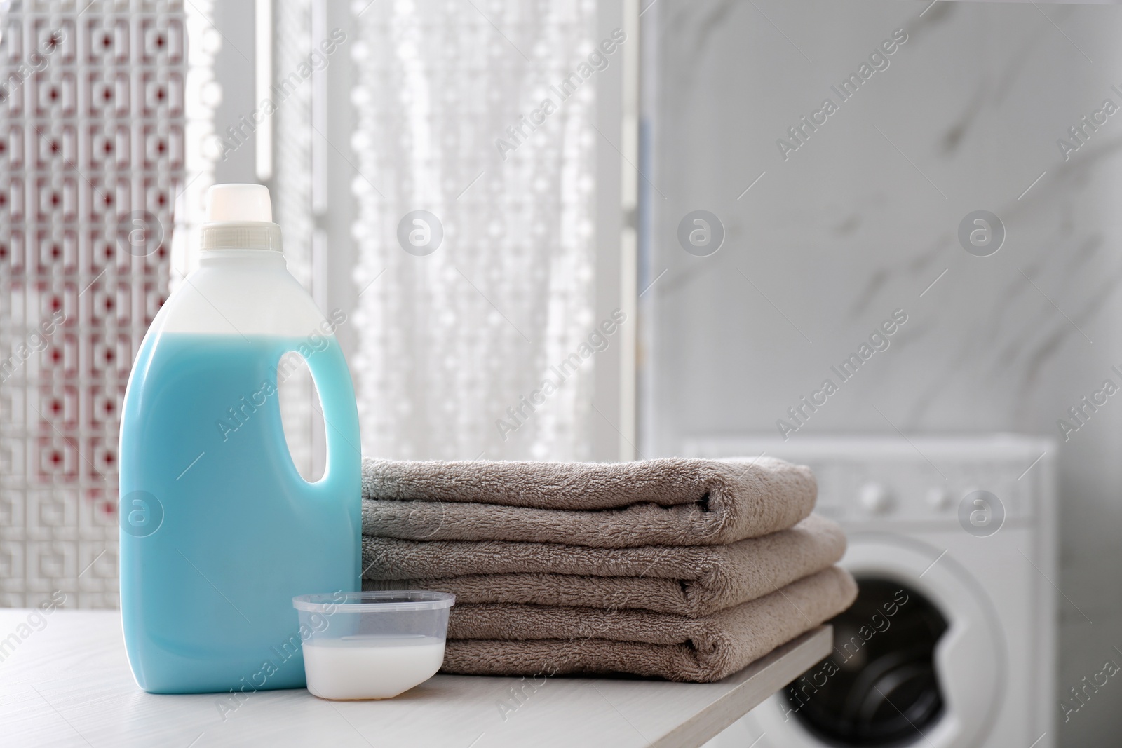 Photo of Stack of folded towels and detergents on white table in bathroom