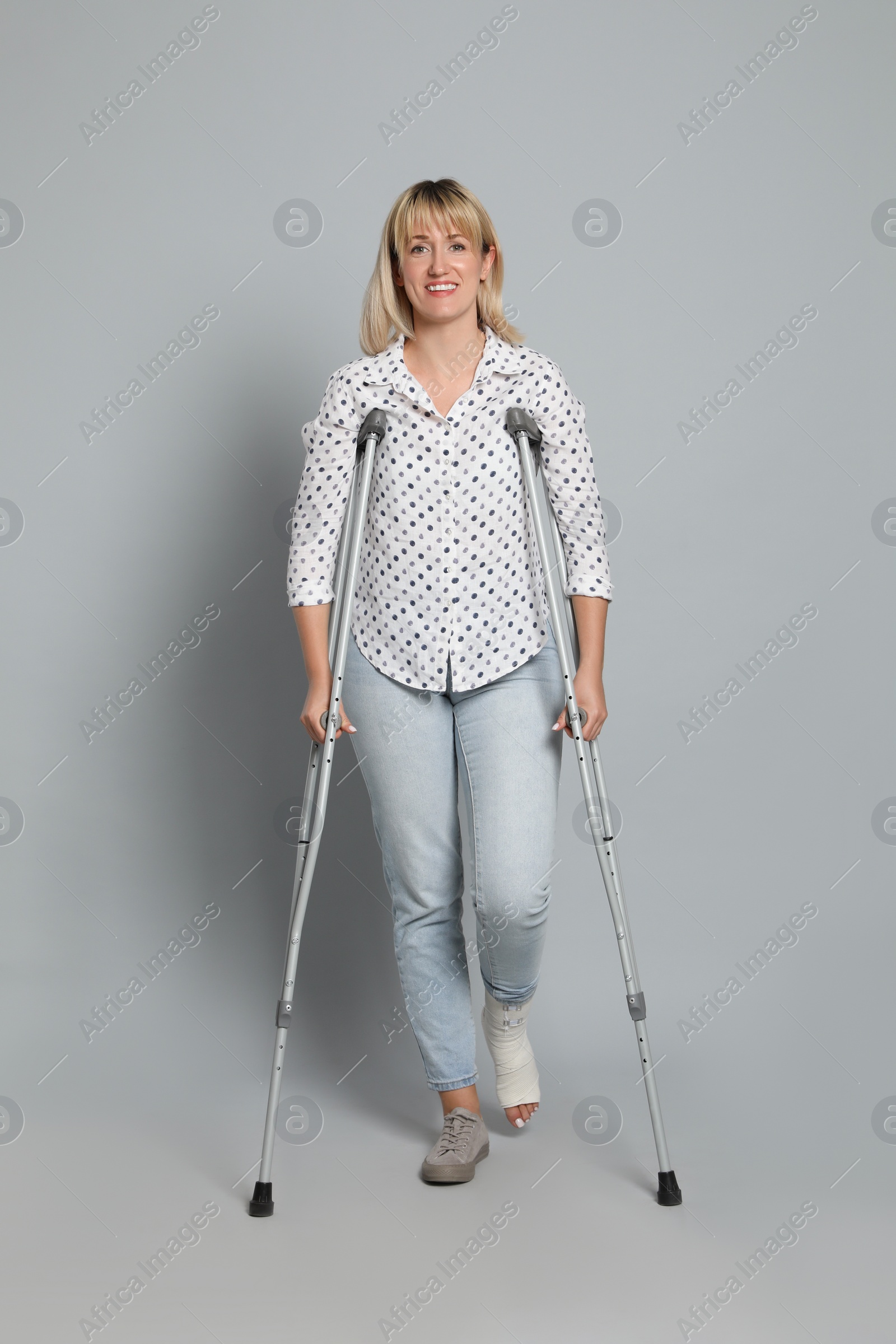 Photo of Full length portrait of woman with crutches on grey background