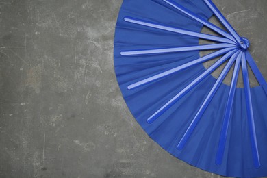 Bright blue hand fan on grey background, top view. Space for text