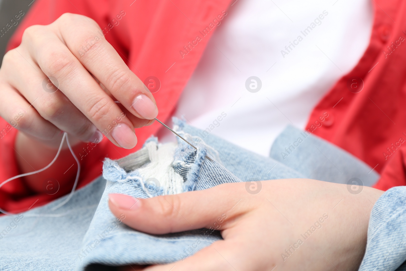 Photo of Woman sewing jeans with needle, closeup view