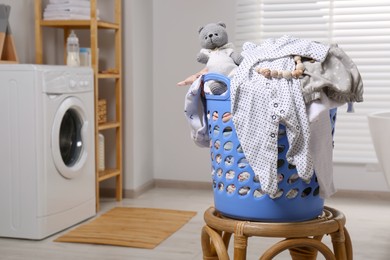 Photo of Laundry basket with baby clothes and crochet toy in bathroom, space for text