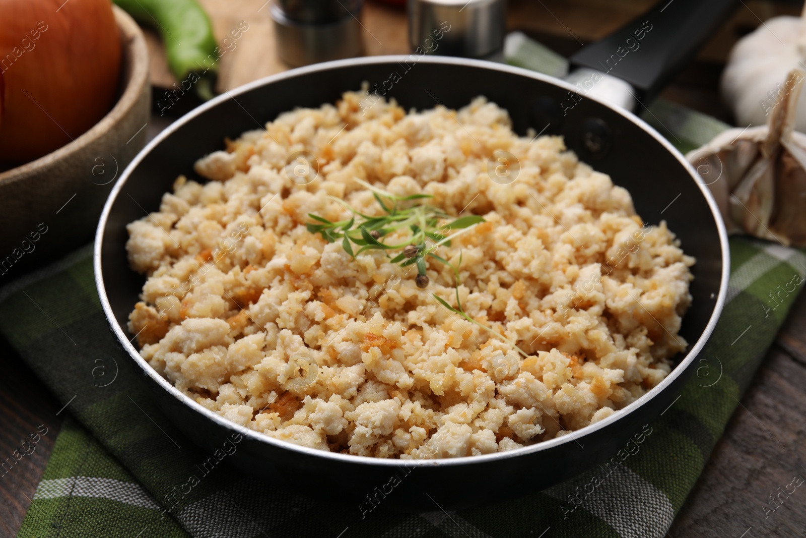 Photo of Fried ground meat in frying pan and microgreens on table, closeup