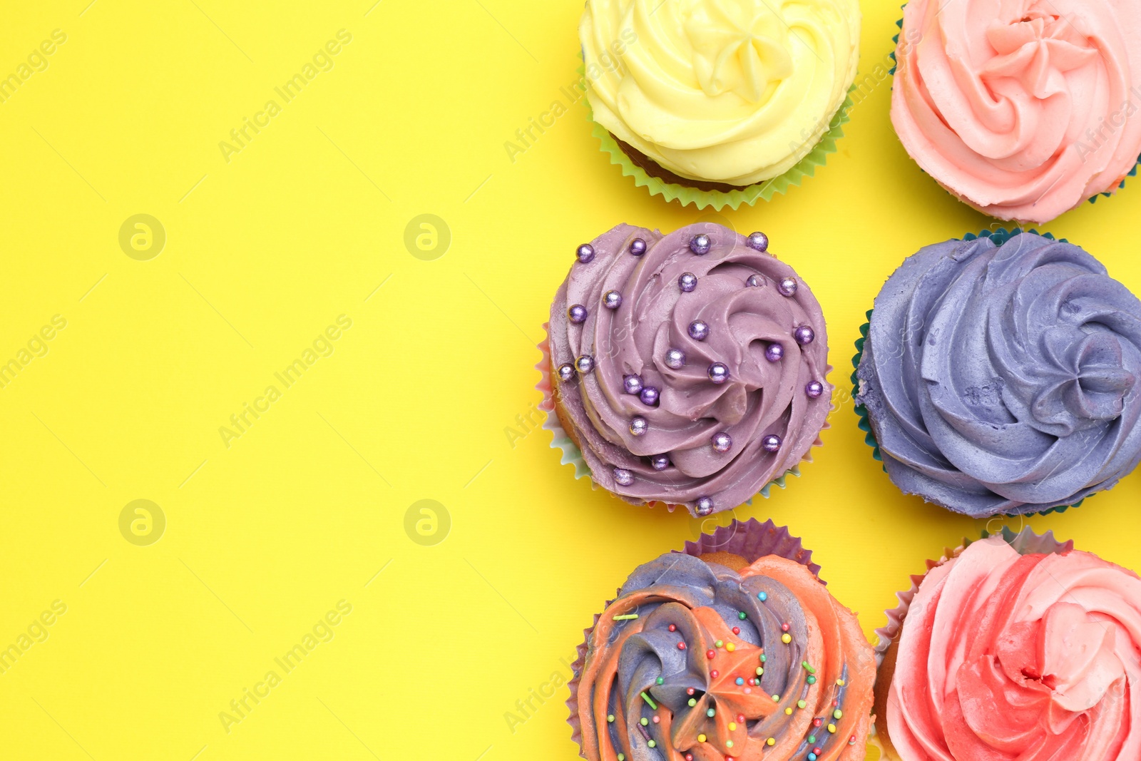 Photo of Delicious cupcake with bright cream on yellow background, flat lay. Space for text