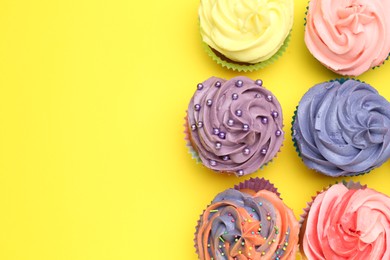 Photo of Delicious cupcake with bright cream on yellow background, flat lay. Space for text