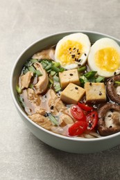 Photo of Bowl of delicious ramen on grey table. Noodle soup