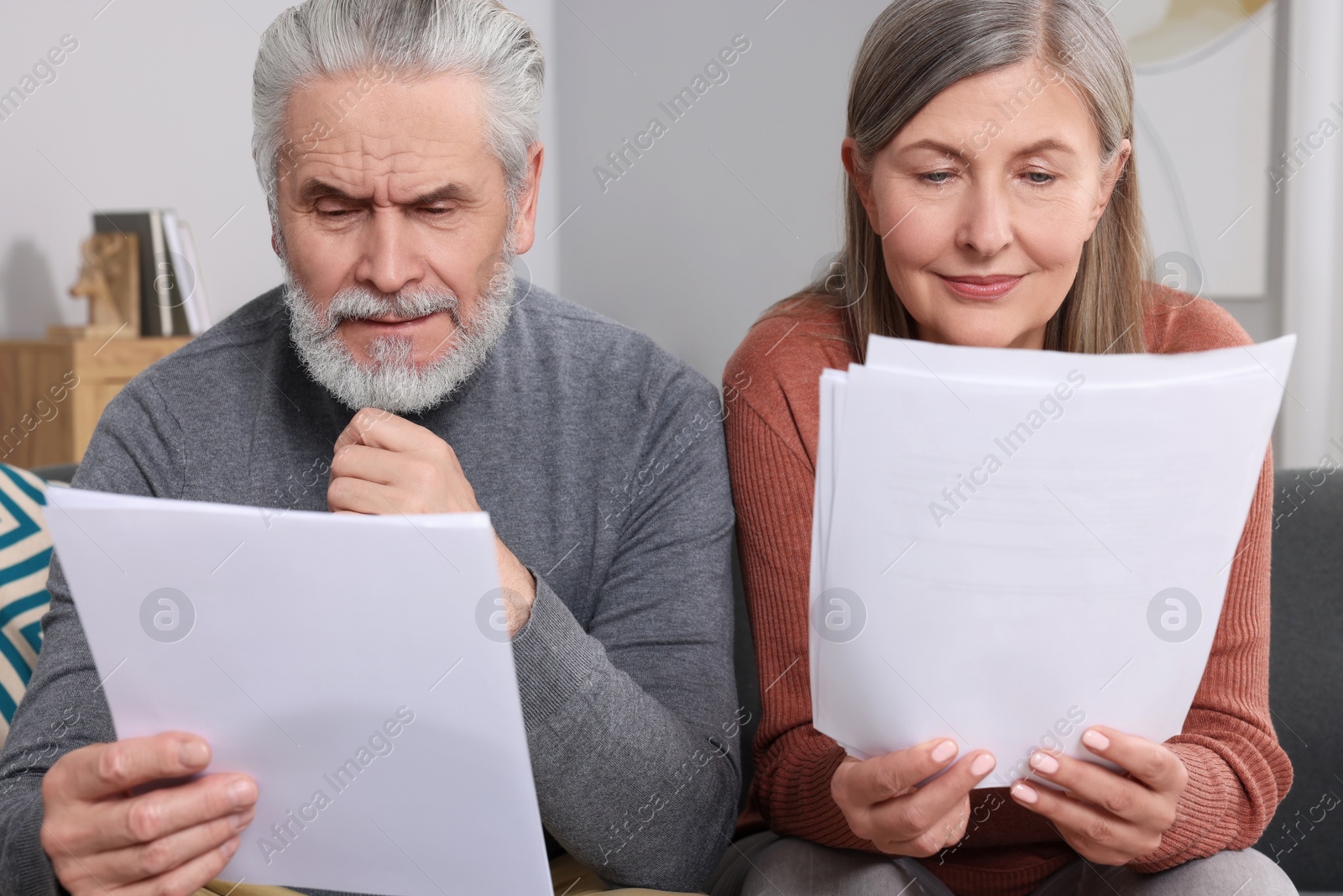 Photo of Elderly couple with papers discussing pension plan in room