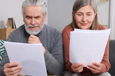 Photo of Elderly couple with papers discussing pension plan in room