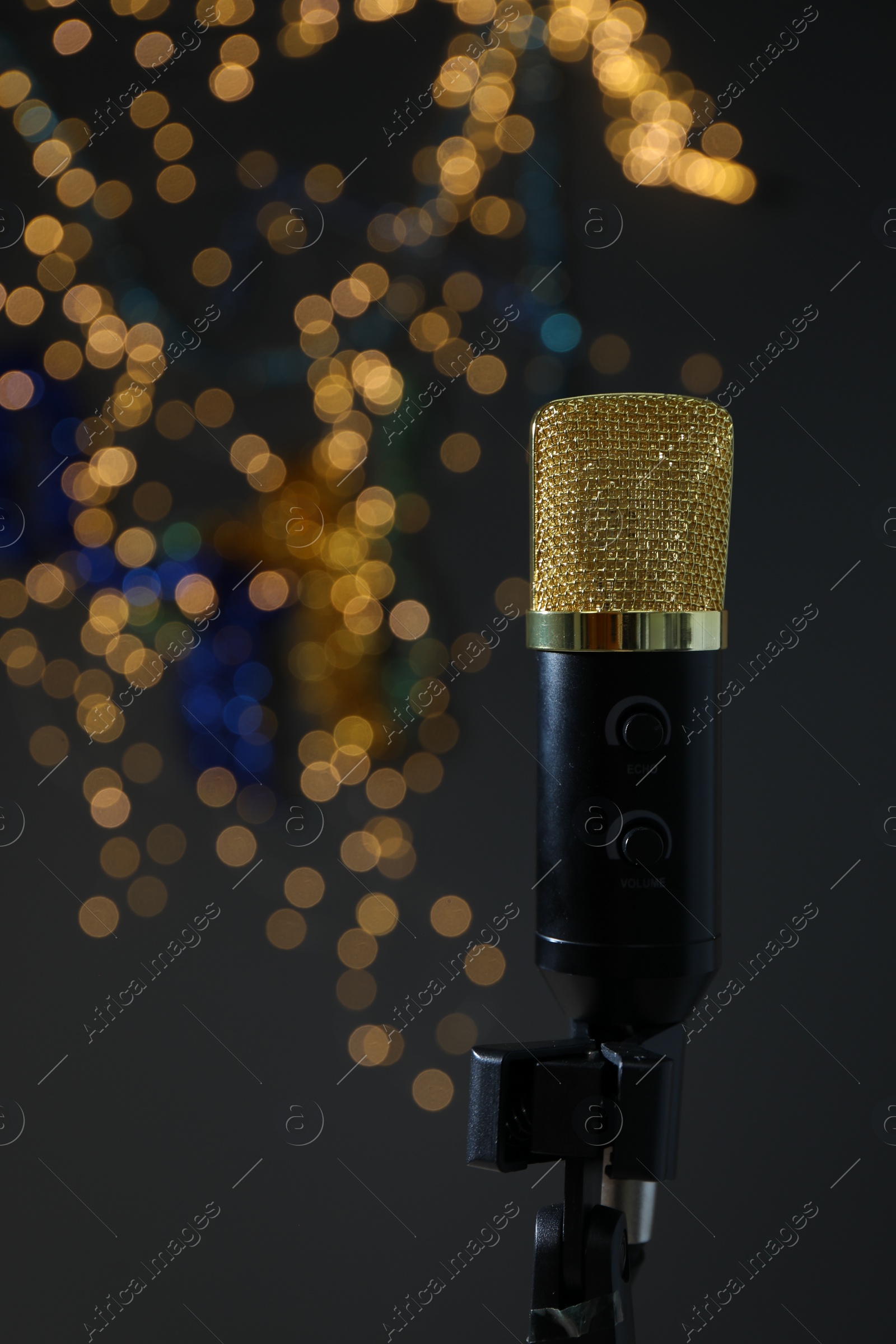 Photo of Microphone against dark grey background with blurred lights. Sound recording and reinforcement