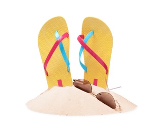 Yellow flip flops in sand and sunglasses on white background