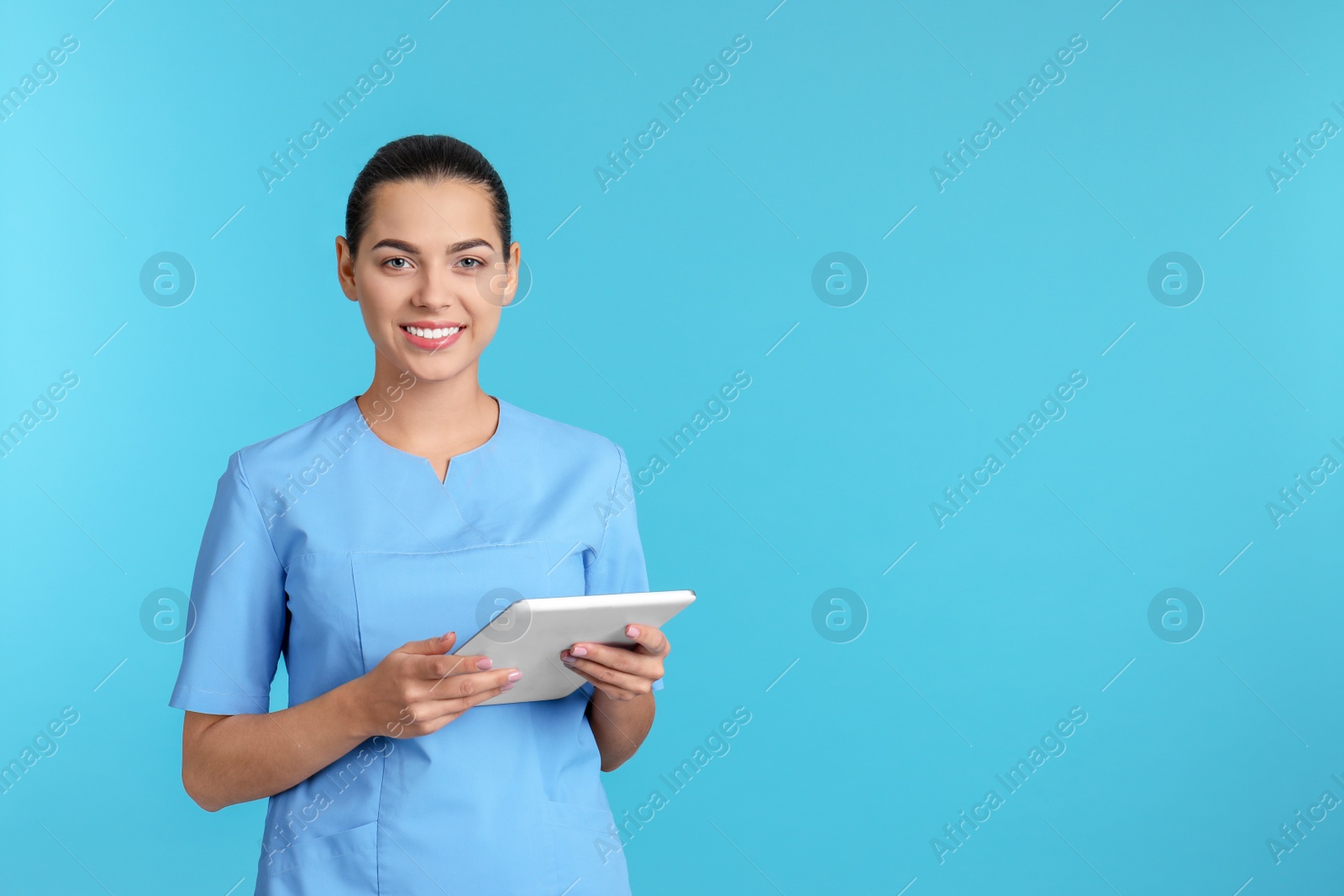 Photo of Portrait of young medical assistant with tablet on color background. Space for text