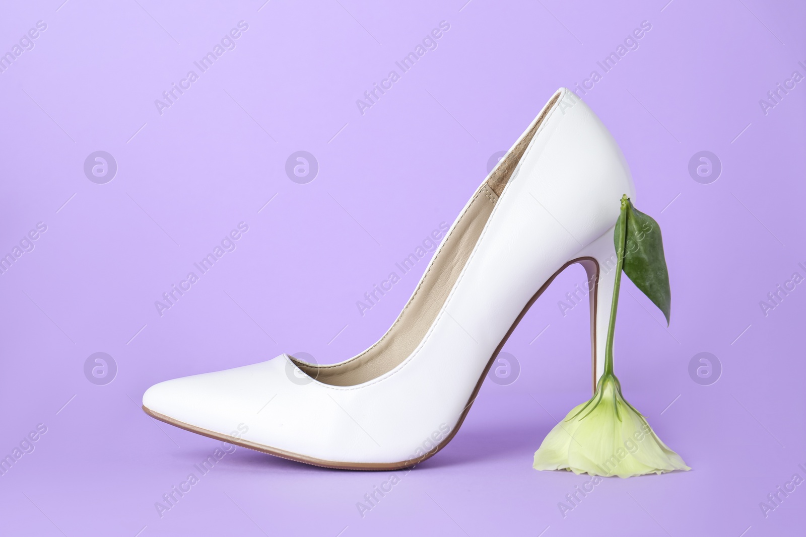 Photo of Stylish women's high heeled shoe with beautiful flower on violet background