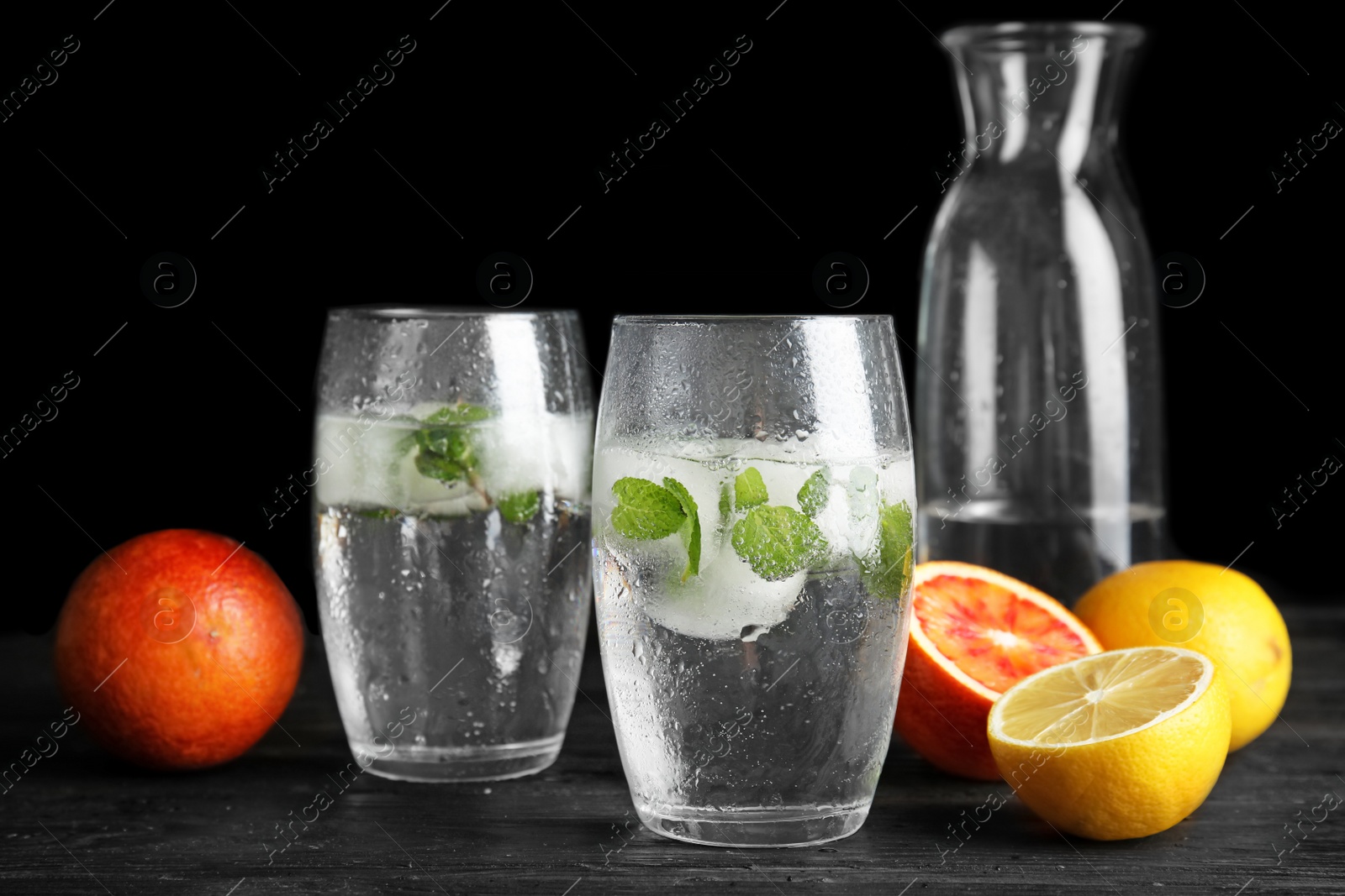 Photo of Composition with refreshing drink with mint and ice cubes in glasses on dark background