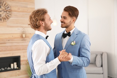 Happy newlywed gay couple dancing at home