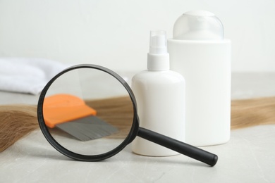 Photo of Cosmetic products, lice comb, magnifying glass and strand of hair on light table