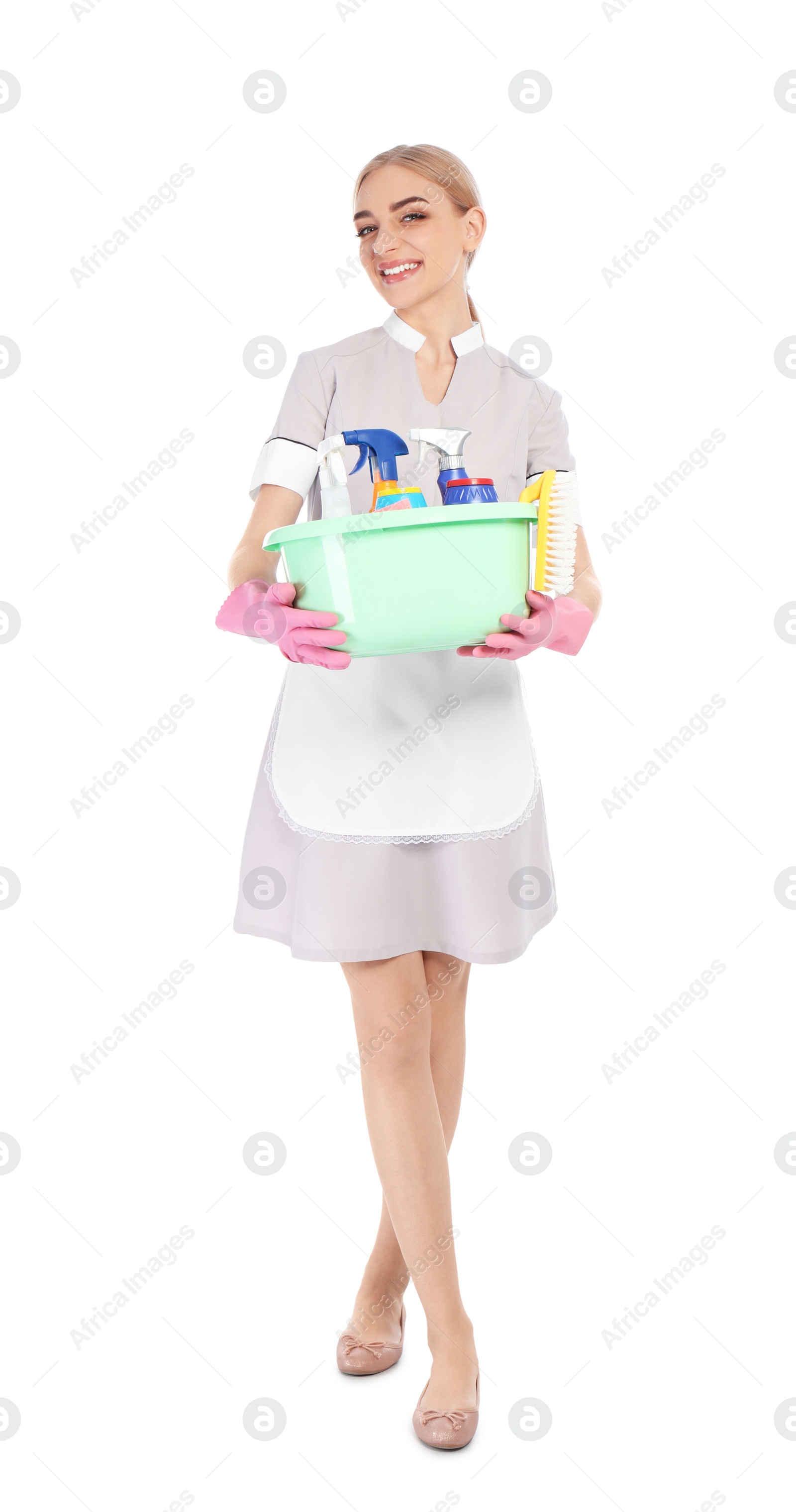 Photo of Young chambermaid holding plastic basin with detergents on white background