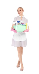 Young chambermaid holding plastic basin with detergents on white background