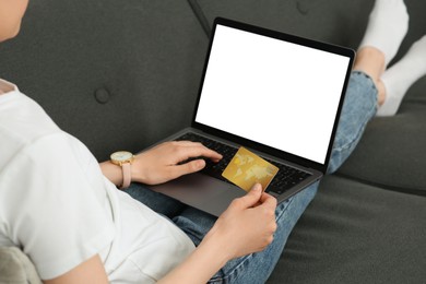 Photo of Woman with credit card using laptop for online shopping on sofa, closeup