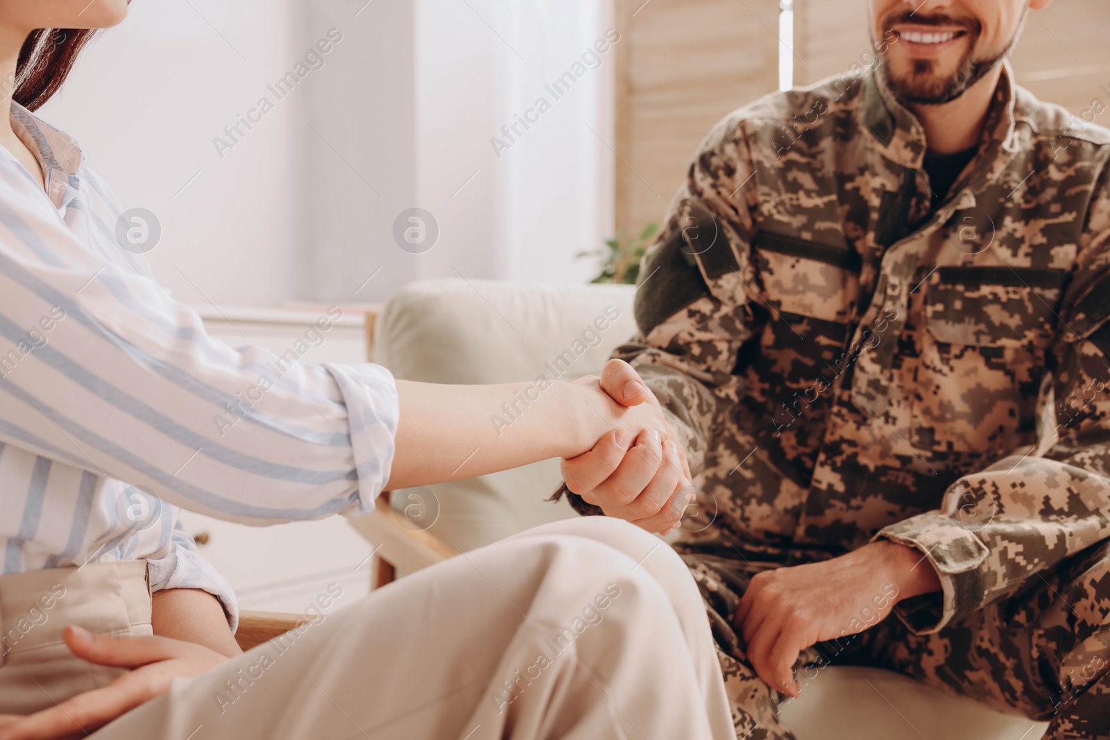 Photo of Psychologist shaking hands with military officer indoors, closeup