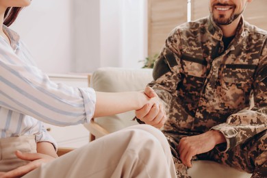 Psychologist shaking hands with military officer indoors, closeup