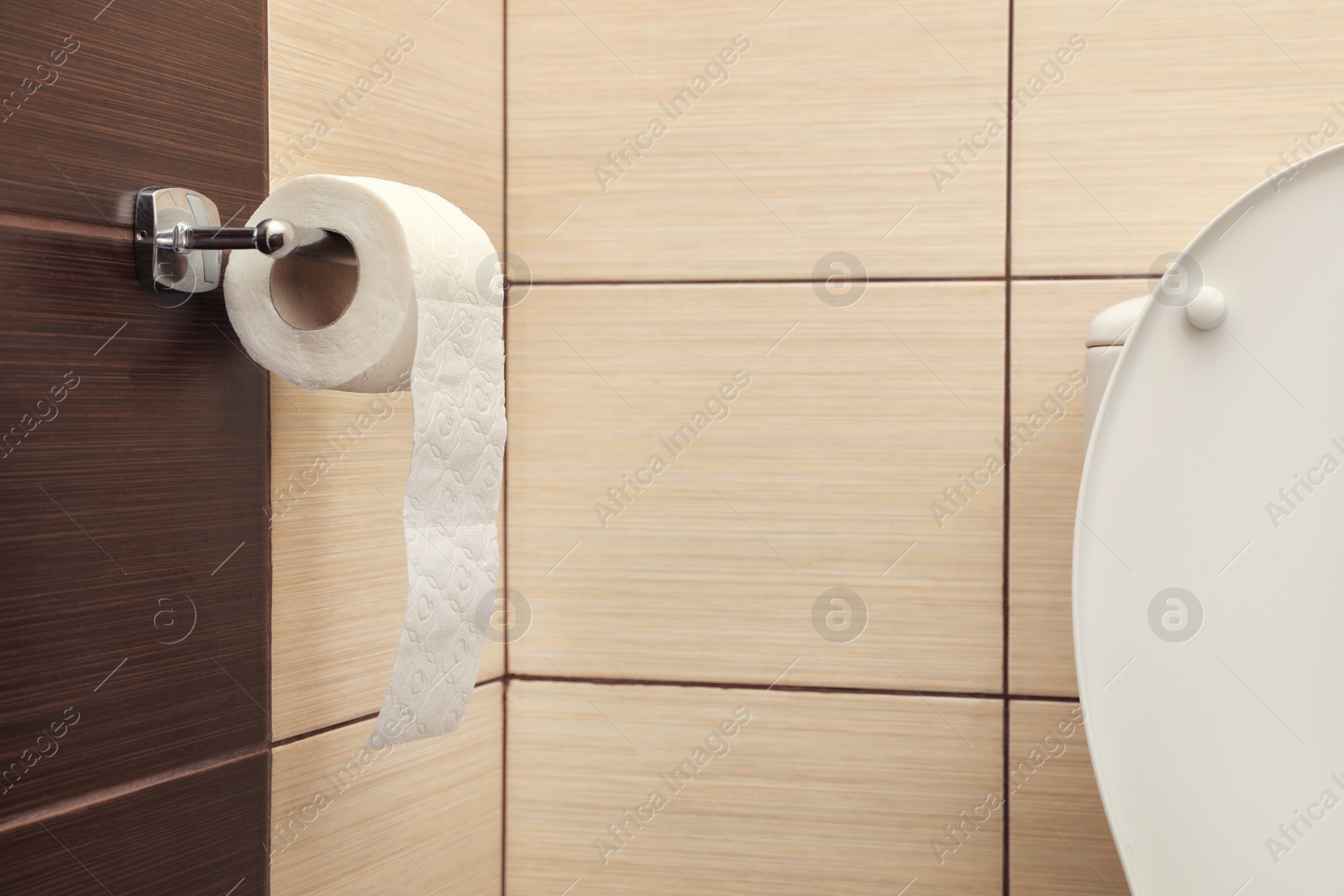 Photo of Holder with soft toilet paper roll in bathroom. Space for text