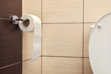 Holder with soft toilet paper roll in bathroom. Space for text