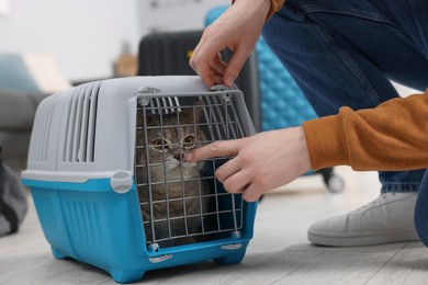 Photo of Travel with pet. Man closing carrier with cat indoors, closeup