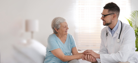 Doctor visiting senior patient in modern hospital, space for text. Banner design