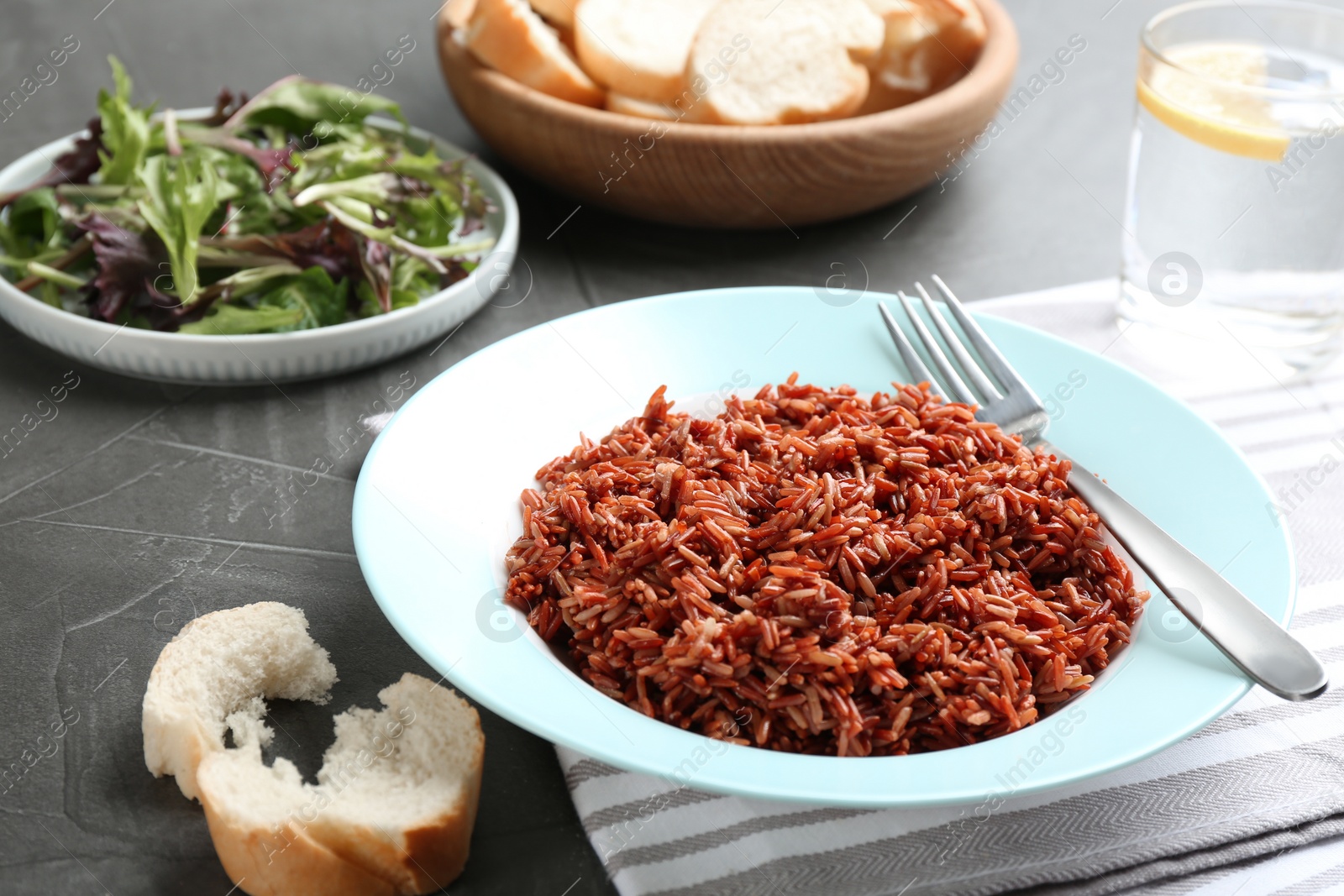 Photo of Tasty brown rice served on dark grey table