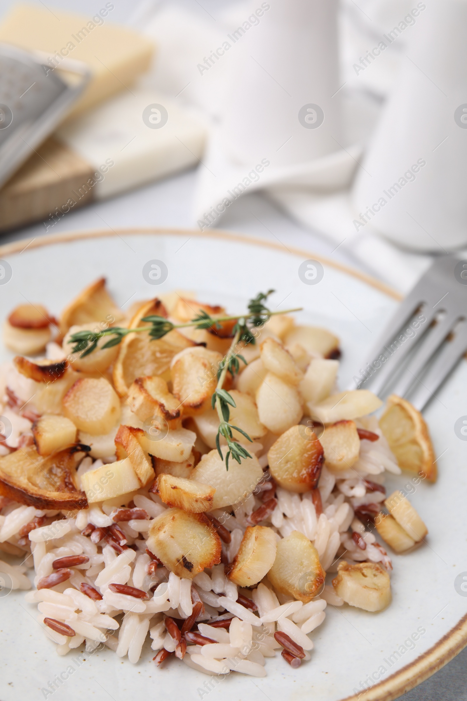 Photo of Plate with baked salsify roots, lemon and rice on table, closeup