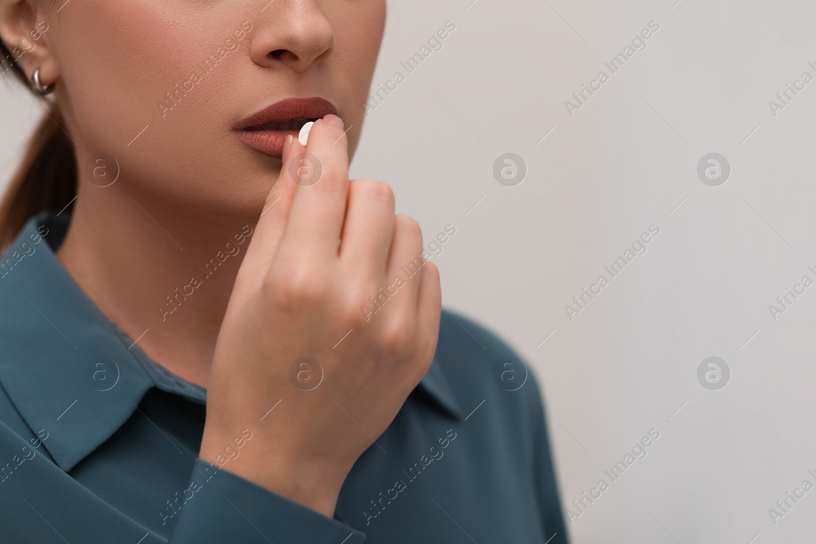 Photo of Woman taking antidepressant pill on light background, closeup. Space for text