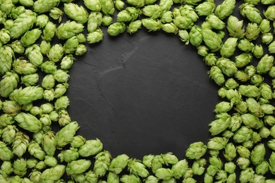 Frame of fresh green hops on black table, flat lay. Space for text