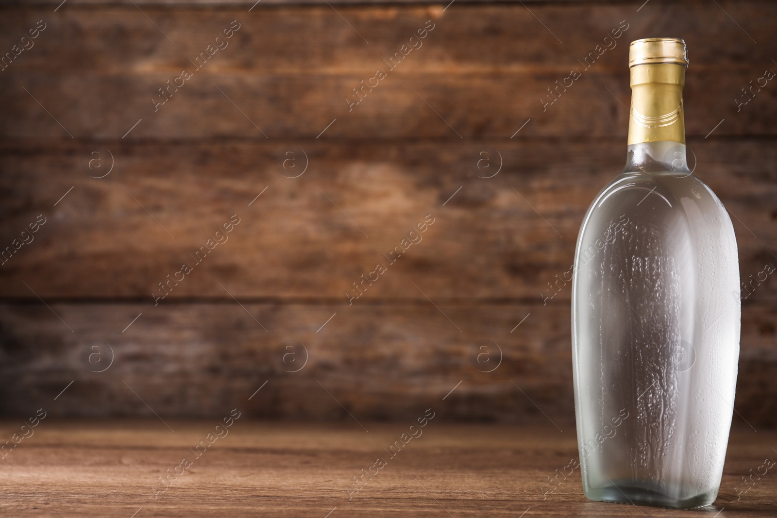 Photo of Bottle of vodka on table against wooden background. Space for text