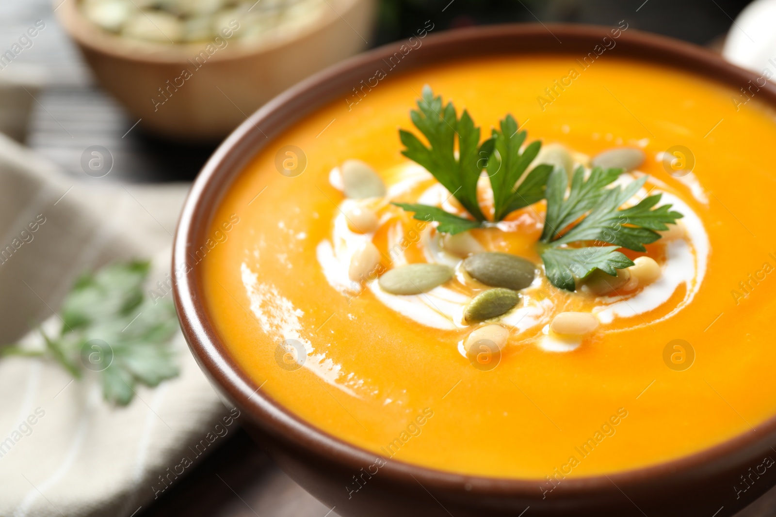 Photo of Delicious pumpkin soup in bowl on table, closeup