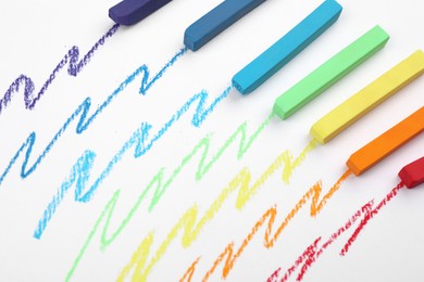 Photo of Colorful pastel chalks and scribbles on white background, above view. Drawing materials
