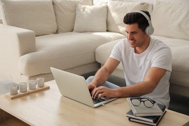 Man with laptop and headphones at table indoors