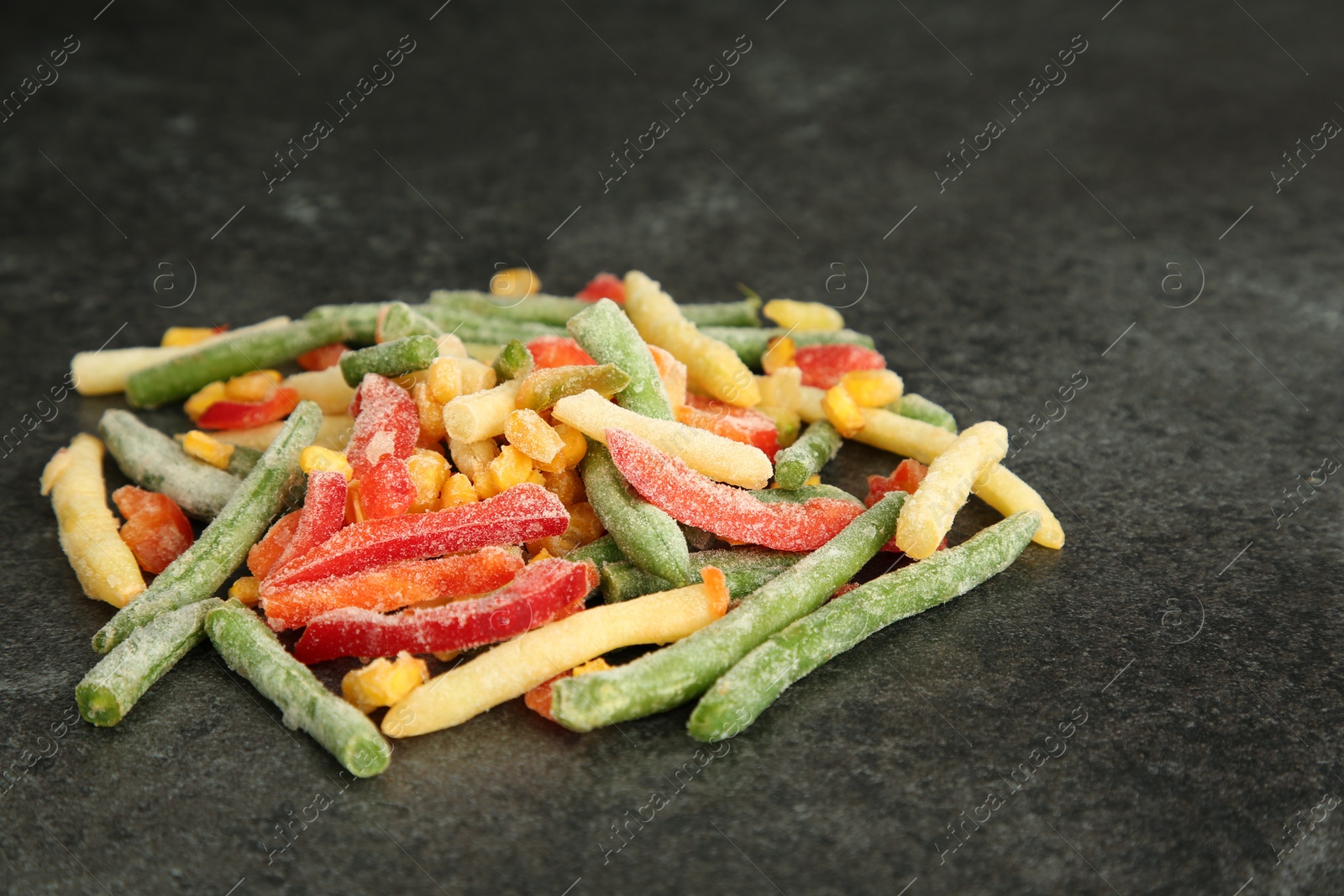 Photo of Mix of different frozen vegetables on gray table, closeup