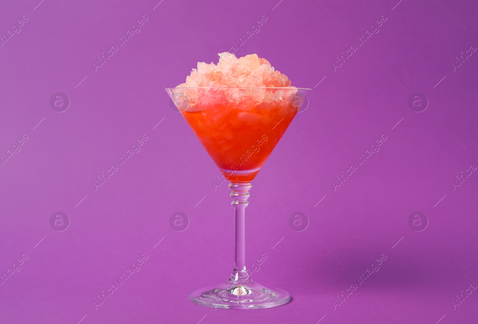 Photo of Shaving ice in martini glass on violet background