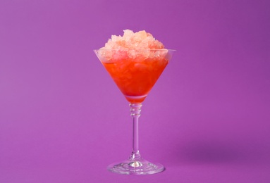 Photo of Shaving ice in martini glass on violet background