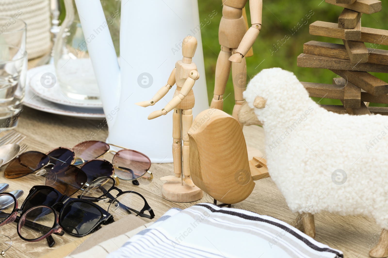 Photo of Many different decorative items on wooden table outdoors. Garage sale