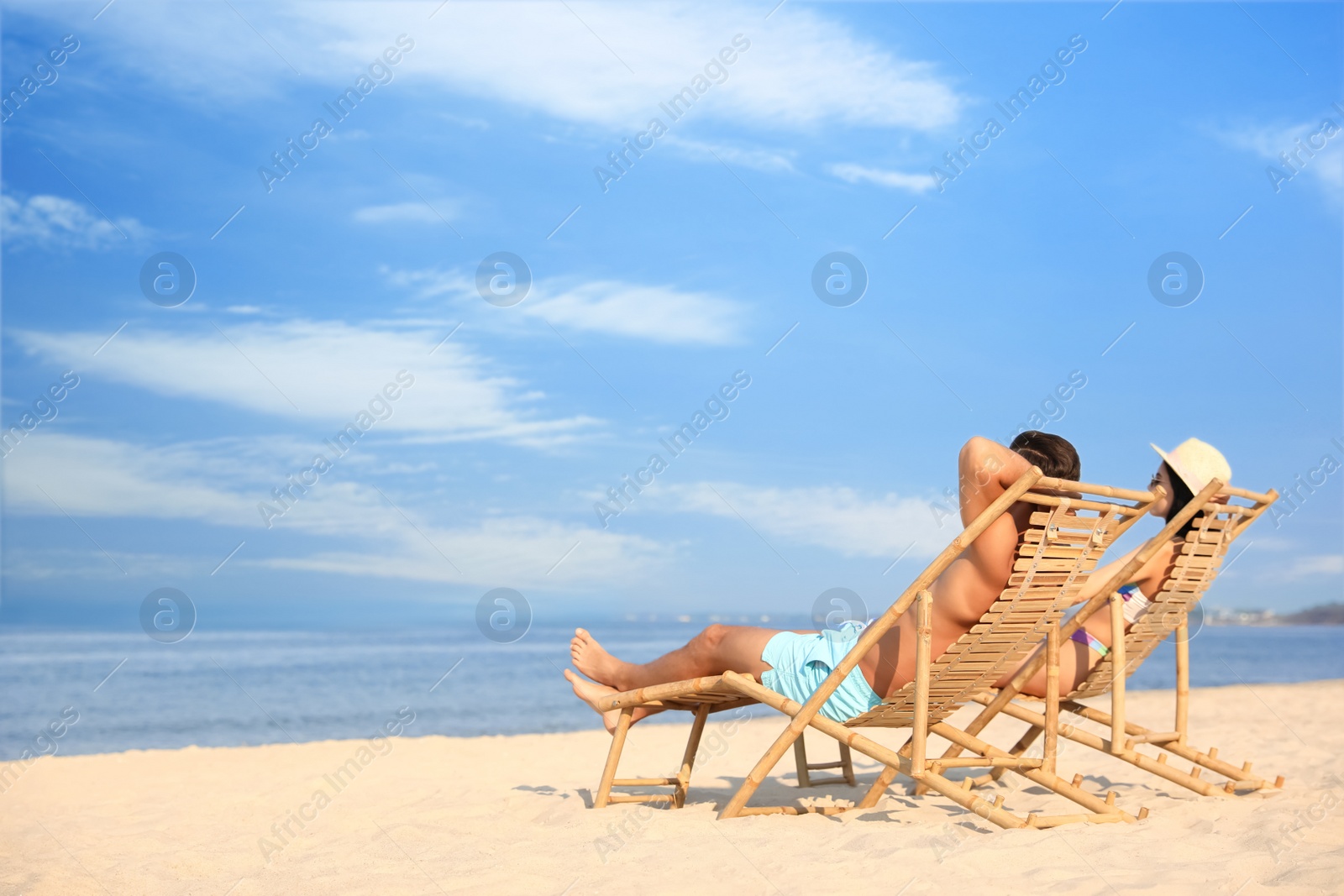 Photo of Couple resting on sunny beach at resort. Space for text