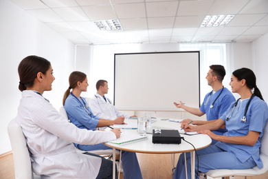 Team of doctors using video projector during conference indoors