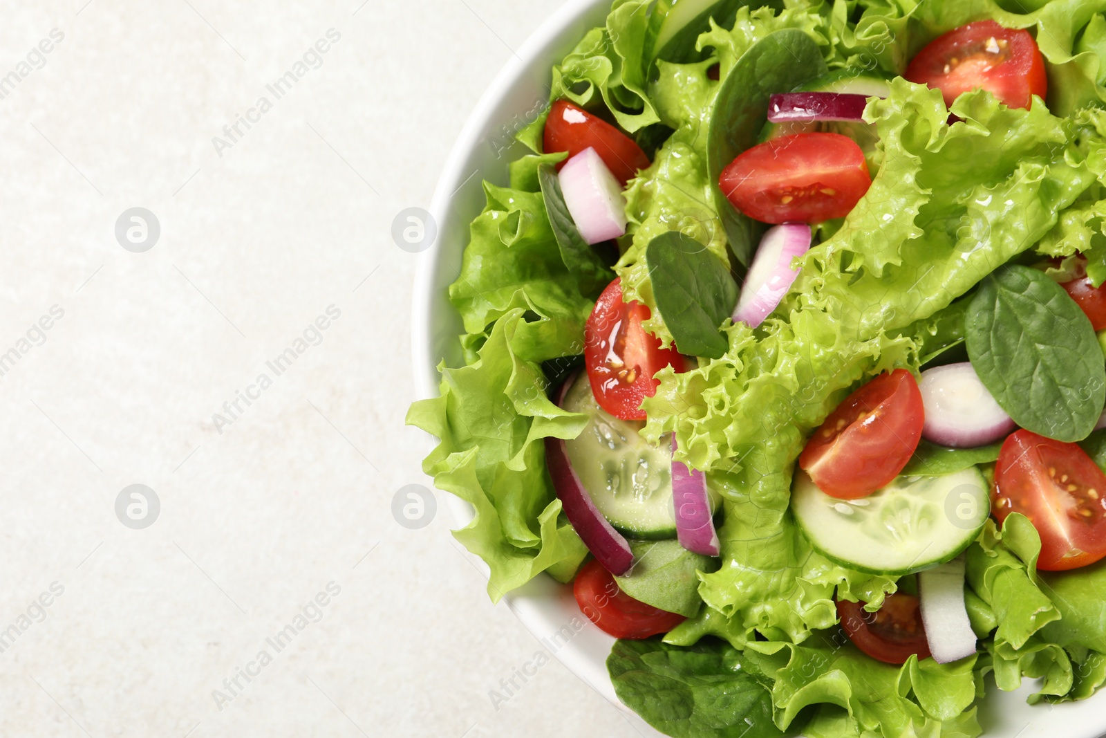 Photo of Delicious salad in bowl on light grey table, closeup. Space for text