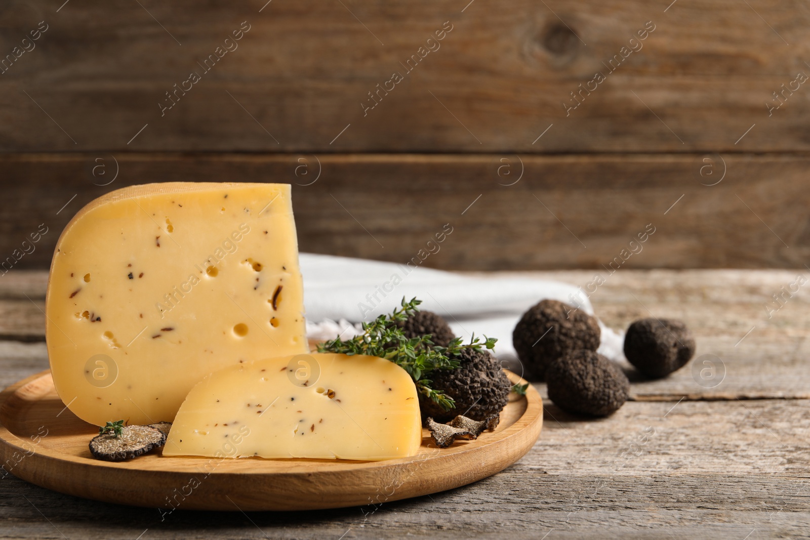 Photo of Delicious cheese, fresh black truffles and thyme on wooden table. Space for text