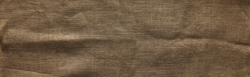 Burlap fabric on wooden table, top view